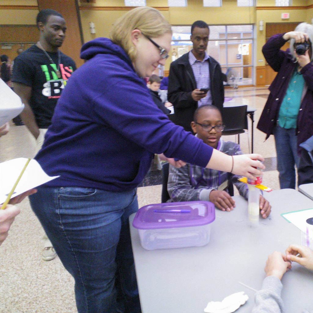 A volunteer Engineering Design Challenge Judge tests a student prototype at the 2014 Dallas Divisional Math & Science Competition, hosted at Tarrant County College.