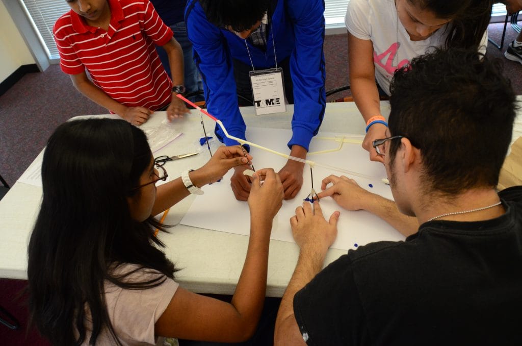 Five students of different ages work on a prototype of a BB Coaster.